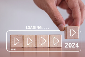 Loading countdown to the new year 2024. Hand holds loading bar on wooden block, year 2023 to 2024,...