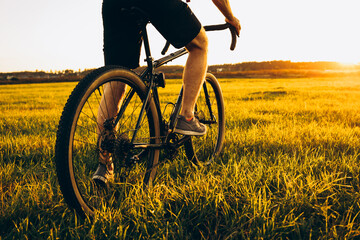 low angle view of cyclist riding mountain bike on rocky trail at sunrise