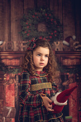 Girl in a Christmas decoration with a doll in her hand