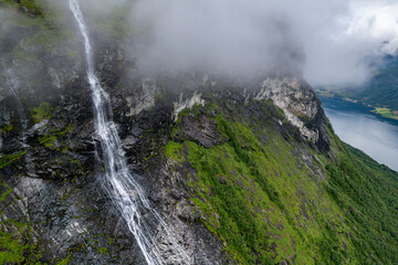 Aerial view of waterfall flowing down cliff into Fjord in Norway