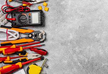 Electrician equipment on marble background with copy space.Top view.Electrician tool set.Multimeter, tester,screwdrivers,cutters,duct tape,lamps,tape measure and wires.Flet lay. © Avocado_studio
