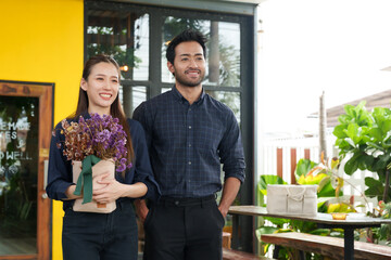 Couple of barista employees A multiracial Indian man and beautiful Asian woman holding bouquet of...