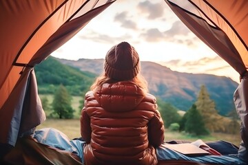 Female traveler camping on the mountain while playing on his phone