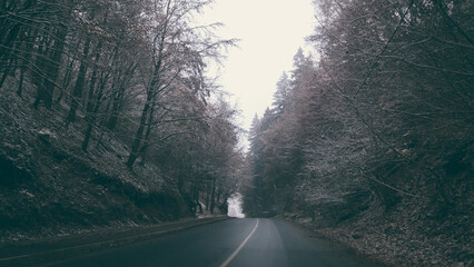 Fairy tale road through the frozen forest from the mountains. Asphalt cleared of snow in the winter...