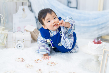 バースデーフォトセットで1歳の誕生日をお祝いして選び取りをする和服姿の可愛い赤ちゃん