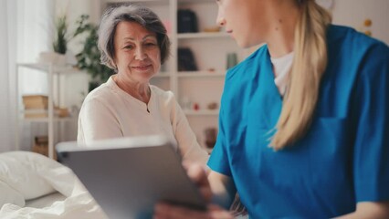 Female physician talking to happy patient in clinic, holding tablet, recovery
