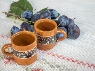 Porcelain coffee cups on a tablecloth with a branch of plums