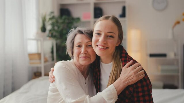 Portrait of happy young woman and grandmother hugging and smiling, family