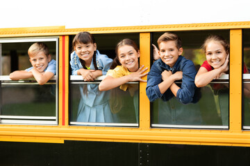 Joyful kids looking out from their school bus window