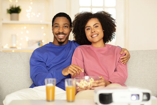 Black husband and wife enjoy movie hugging in living room