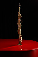 Soprano saxophone on surface of a red piano against black background. Copy space. Shallow depth of...
