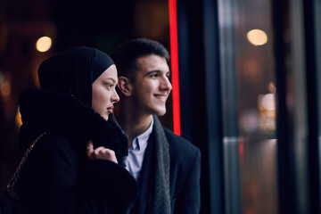 Happy multicultural business couple walking together outdoors in an urban city street at night near...