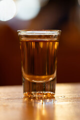 close up of shot glass on wood table with blur restaurant background