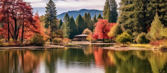 In the tranquil autumn park the beautiful landscape captured my attention with its lush green forests majestic mountains and vibrant colors of red orange and yellow all under the clear blue  - obrazy, fototapety, plakaty