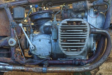 Fototapeta premium part of a closed old retro rusty heavy powerful engine in an iron crankcase with an exhaust pipe and a winding lever from an retro vintage motorcycle on the street 