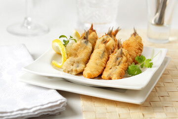 Small battered and fried fish appetizer served on a white plate.