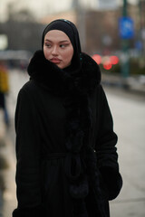 Muslim woman walking on an urban city street on a cold winter night wearing hijab