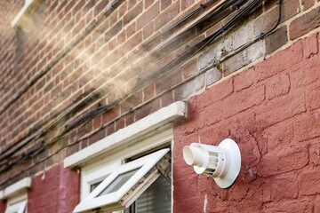 Boiler vent billowing steam next to an open window.