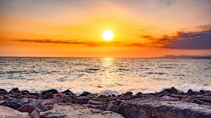 Vibrant sunset sky glows over a picturesque rocky beach