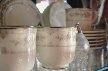 Vintage china dinnerware set in a floral design with teacups, plates, and salt shaker closeup 