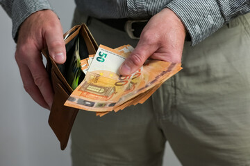 
a guy pulls money out of his wallet and counts it, financial crisis associated with money...