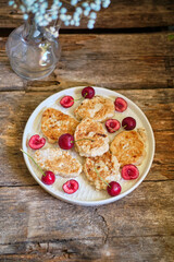 Pancakes with oatmeal and cherries. Top view, wooden background.