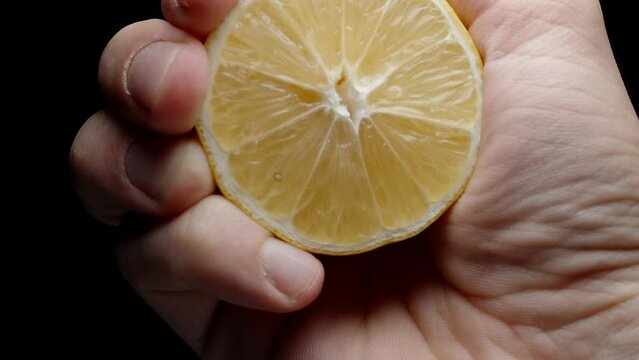 I squeeze the juice from half a lemon. Slow-motion view from below, drops appear to be flying towards you. Close-up.