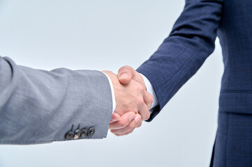 Two men in suits are shaking hands.