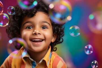Fototapeta premium happy smiling indian child boy on colorful background with rainbow soap balloon with gradient