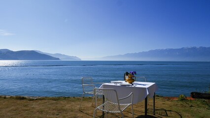 A tranquil outdoor setting featuring a table and two chairs situated near a body of water