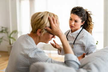 Obraz na płótnie Canvas Young concerned female medical practitioner reassuring worried patient that everything is going to be okay. Sad woman patient with female doctor.