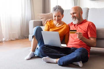 Elderly couple shopping online with credit card and laptop at home