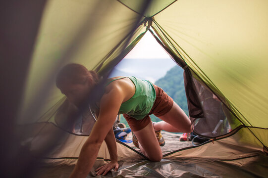 A young woman sets up sleeping bags inside a tent overlooking a gorge on a cliff in Tennessee