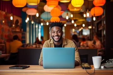 happy african american man sitting at table with laptop in cafe
