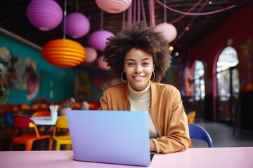 happy african american woman sitting at table with laptop in cafe