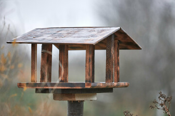 Handmade wooden bird feeder. Bird feeder made of plywood standing on a post.