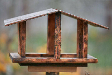 Handmade wooden bird feeder. Bird feeder made of plywood standing on a post.