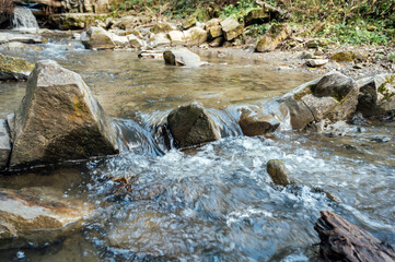 Naklejka na ściany i meble Wild mountain river flowing through stone boulders. Abundant clear stream in carpathians.