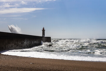 Felgueiras Lighthouse in Porto on the Atlantic coast with huge waves in a sunny day, splashing...