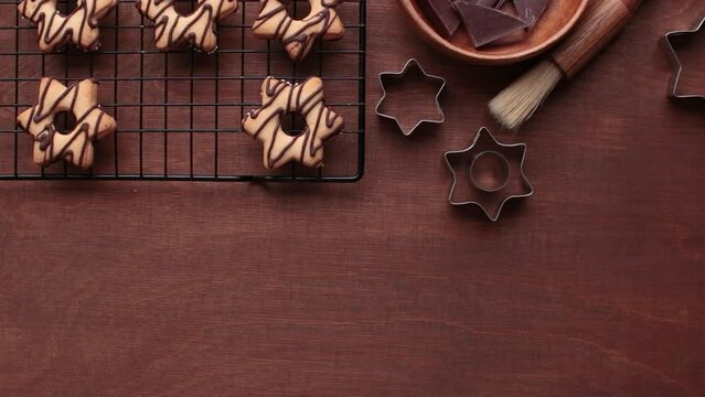 A human's hand picks up a fresh homemade star-shaped cookie with chocolate from the table