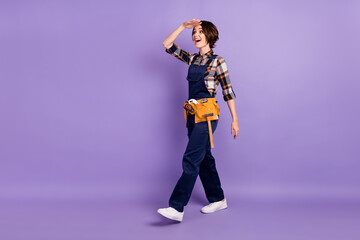 Full size profile side photo of young woman happy smile repairer go walk look ahead isolated over violet color background