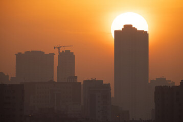 Naklejka premium Sunrise emerging from the back of the building at Tubli bay, Bahrain