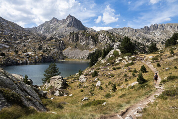 Hiker in a beautiful landscape of the natural park of Aigestortes y Estany de Sant Maurici, Pyrenees valley with river and lake