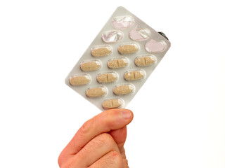 Male hand holding vitamin tablets with typical shape, tablets isolated on white background. Hand...
