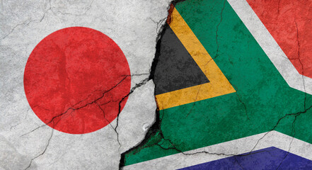 Japan and South Africa flags, concrete wall texture with cracks, grunge background, military conflict concept