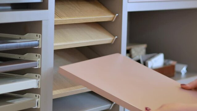 Women's hands and samples of laminated chipboard decors in the store external color palette and textures. The choice of material for new furniture.