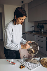 Beautiful woman prepares a banana muffin with berries for breakfast.  healthy homemade food concept. Cozy atmosphere in the kitchen at home