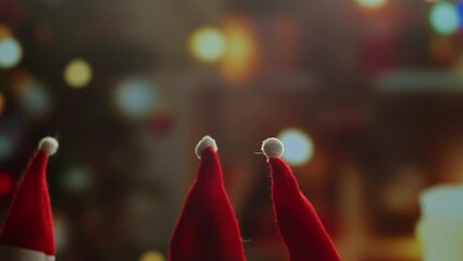 Little Christmas hats on background close-up. Elfs, dwarfs in red hats walking at home near christmas tree. Vibes of winter holidays,2024, 2025