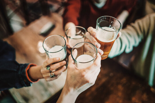 Close-up of a cheerful group of friends toasting with glasses of beer and milk, enjoying a social moment together.