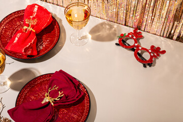 Modern Christmas table setting, red plates with napkins and two glasses of champagne on the festive table copy space for text